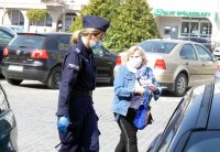 Sierż. Prudek oraz policjantka rozdaje maseczki mieszkańcom Głogówka.