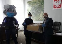 Burmistrz Prudnika Grzegorz Zawiślak przekazuje maseczki ochronne dla dzieci prudnickim policjantom.