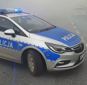 radiowóz policyjny stoi w dymie na ulicy