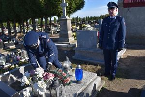 Cmentarz w Przystajni. Młodszy inspektor Waldemar Popczyk składa znicz na grobie rodziny Jasieniów.