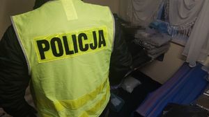 policjant z kamizelką odblaskową stoi przy ubraniach leżących na ziemi