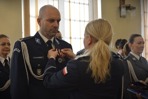 Komendant Wojewódzki Policji w Opolu wręcza medal policjantowi podczas uroczystości Święta Służby Cywilnej na sali w Komendzie Wojewódzkiej Policji w Opolu