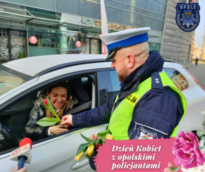 Zdjęcie przedstawia policjantów rozdających kwiaty.
