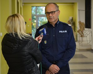 Nadinspektor Jarosław Kaleta udziela wywiadu dziennikarce. Oboje stoją na korytarzu uczelni.