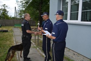 policjant otrzymuje nagrodę z rąk komendanta