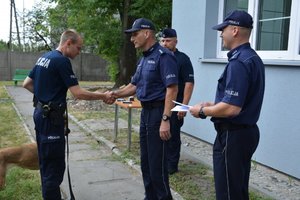 policjant otrzymuje nagrodę i gratulacje od komendanta