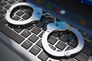 Zdjęcie policyjnych kajdanek na komputerowej klawiaturze