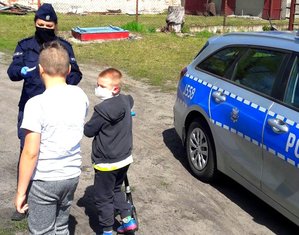 policjant, obok stoją dzieci z nałożonymi maseczkami